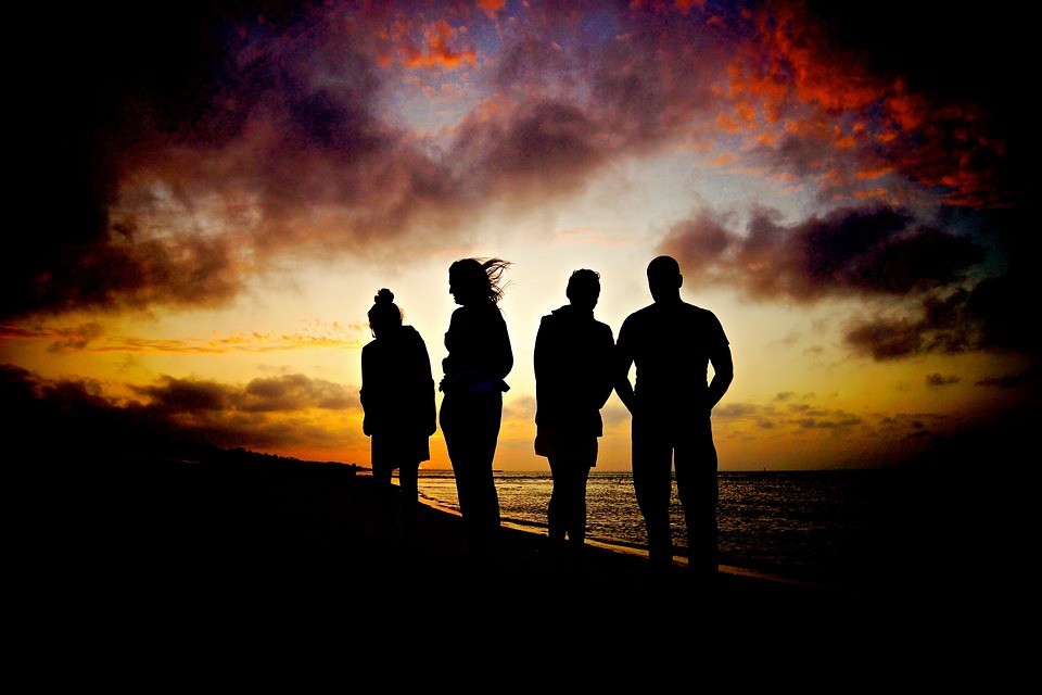 Four silhouettes against a sunset beach background